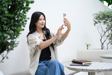 Relaxed asian woman using her smartphone at a garden style coffee shop table
