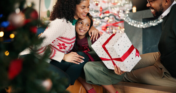 Christmas, family and hug child with gift for thank you, gratitude or celebration. Present, mom and dad embrace kid for love, care or appreciation with happy African parents in home for xmas holiday