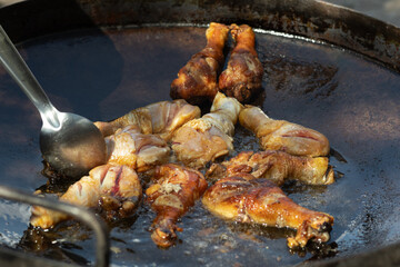 Chef frying chicken legs on large pan outdoors