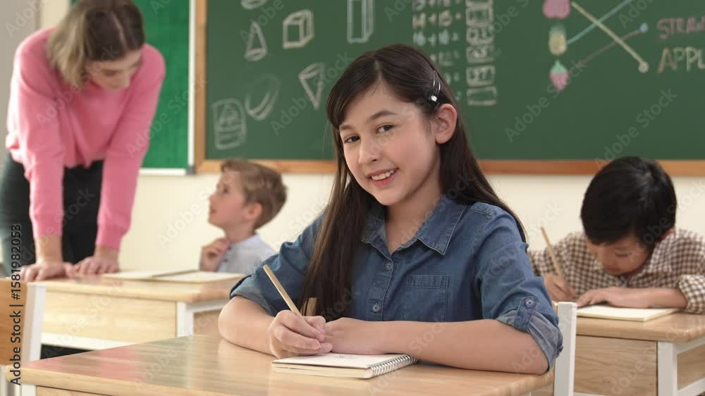 Poster asian girl writing test or classwork while looking at camera at classroom. diverse happy student tak
