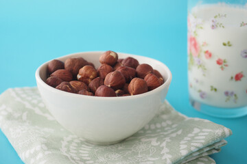 Bowl of hazelnuts with glass of milk on a table