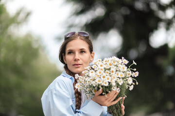 Woman Daisies Bouquet: Pensive girl holds flowers outdoors during day, evoking carefree summer...