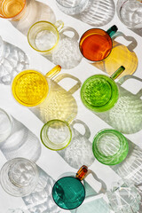 Colored shiny drink Glasses still life with shadow and sunlight reflections on white, minimal...
