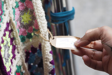 Hand reaching for a tag on a colorful crochet blanket