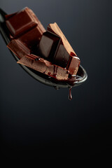 Melting pieces of bitter chocolate on a black background.