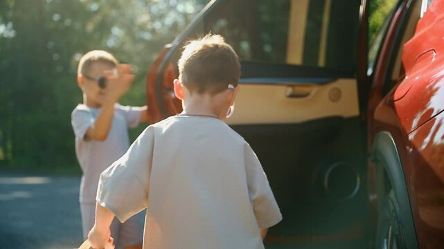 Two little boys loading baggage into car to get to airport. Small cheerful children going on trip during holidays to play, enjoy rest and have fun. Concept of carefree childhood and summer travelling.