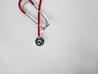 Stethoscope with red tubing placed on white surface illustrating medical tools and healthcare