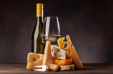 Assorted cheeses paired with glass of wine on a rustic table