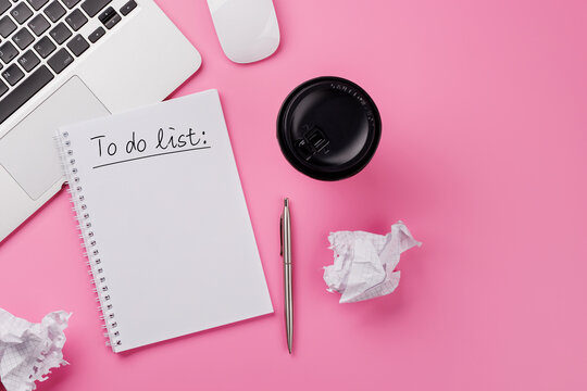 Stylish pink desk with laptop, coffee cup, office supplies, and a notepad for writing a to-do list