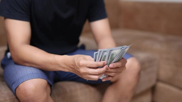 Man sit and count money at sofa in room
