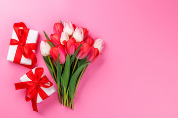Pink tulip bouquet and gift boxes on a soft pink background