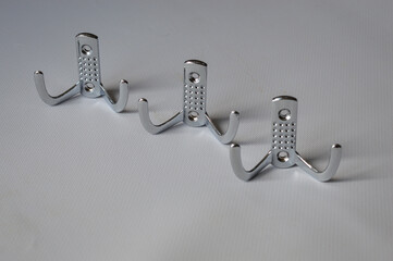 set of three metal wall hooks aligned on white background, ideal for concepts of home storage,...