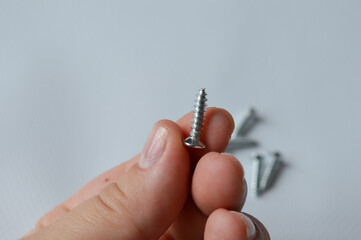 close-up of a person holding a small metal screw, concept of home improvement, hardware details,...