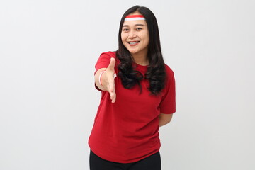Indonesian woman wearing red and white ribbon celebrating Indonesian independence day smiling while standing extending hand in handshake gesture looking at camera, isolated on white background.