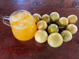 Yellow passion fruit juice in a glass and fresh passion fruit on wooden table