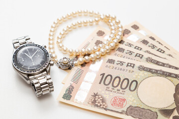 真珠のネックレスと腕時計とお金