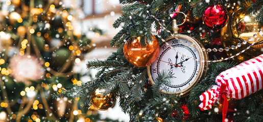 The clock hands on the dial show 12 o'clock. Golden retro clock on a Christmas tree. Beautiful...