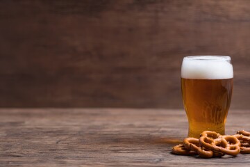 Golden beer in frosty glass paired with traditional pretzels on