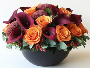 Stunning floral arrangement features vibrant orange roses, deep burgundy calla lilies, and textured pink protea, beautifully arranged in sleek black vase. lush greenery adds fresh touch