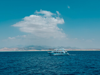 White yacht sailing calm blue sea near desert coast on sunny day