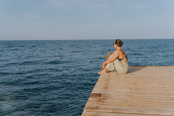 Young woman relaxing and enjoying the ocean view from a wooden pier