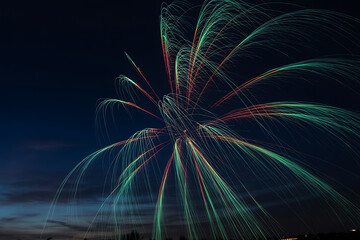 Colorful explosion of fireworks lights up the dark night sky with vibrant green, red, and blue streaks during festival.