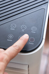 Gros plan sur une main appuyant sur le bouton d’un climatiseur.