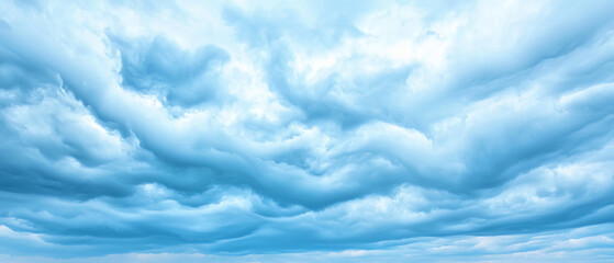 A panoramic view of a dramatic sky filled with thick, layered clouds in various shades of blue and white.