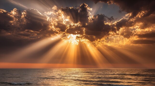 Light beams piercing through clouds above wide ocean expanse