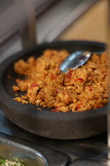 Spicy Indonesian sambal made from mashed tempeh and chili, served in a traditional stone mortar.