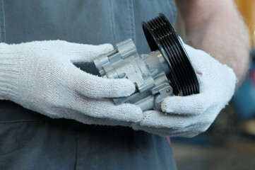 Car service. Auto parts. The car's power steering pump. An auto mechanic prepares a new power...