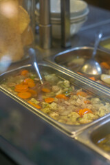 Authentic Indonesian clear broth soup featuring tender beef, carrots, cauliflower, and peas, served hot in a stainless steel container