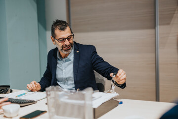 A professional man smiling at a desk in an office, conveying confidence and warmth. Various office...