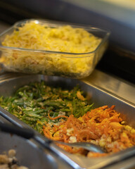 Assorted Indonesian stir-fried vegetables including carrots, cabbage, and green beans served in trays at a traditional food stall or buffet.