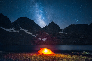 Glowing tent under starry night sky and Milky Way