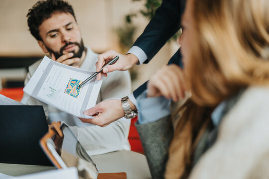Colleagues engaged in a discussion over documents and data, showcasing teamwork and cooperation. - Powered by Adobe