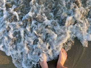 Enjoying the gentle waves at the beach during sunset while feeling the cool sand between toes