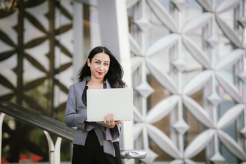Confident, determined businesswoman
Standing in front of a modern office building holding a laptop,...