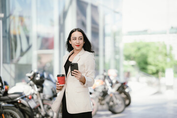 A businesswoman in a chic white blazer and holding a cup of coffee represents modern elegance,...