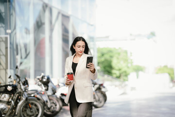 A businesswoman in a chic white blazer and holding a cup of coffee represents modern elegance,...