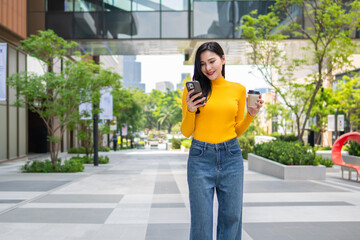 Asian young woman using smartphone while standing in the city. 