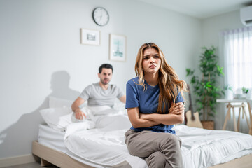 Caucasian young couple sitting on bed with painful after fight argument. 