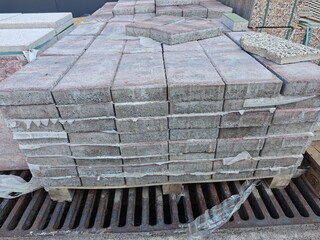 Piles of concrete bricks stored on wooden pallets at a construction site in the early morning hours