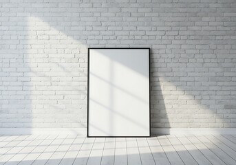 A blank framed poster leans against a white brick wall, illuminated by sunlight.