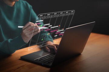 Close-up of a person managing a digital project timeline on a laptop with a pen. Gantt chart...