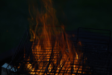 Close-up of Flaming Charcoal Grill in Dark Outdoor Setting - BBQ Flames and Cooking Heat