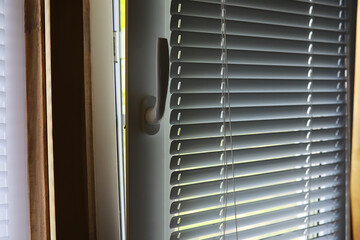 Partially Open Window with Horizontal Blinds Illuminated by Sunlight in a Home Interior Setting