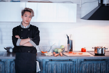 Asian cook in the kitchen prepares food in a cook suit
