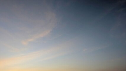 A clear sunrise sky, transitioning from light blue to a faint orange at the horizon, with subtle,...