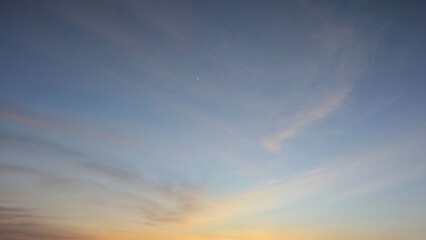 A tranquil sunrise sky over Indonesia, transitioning from deep blue to soft orange near the...